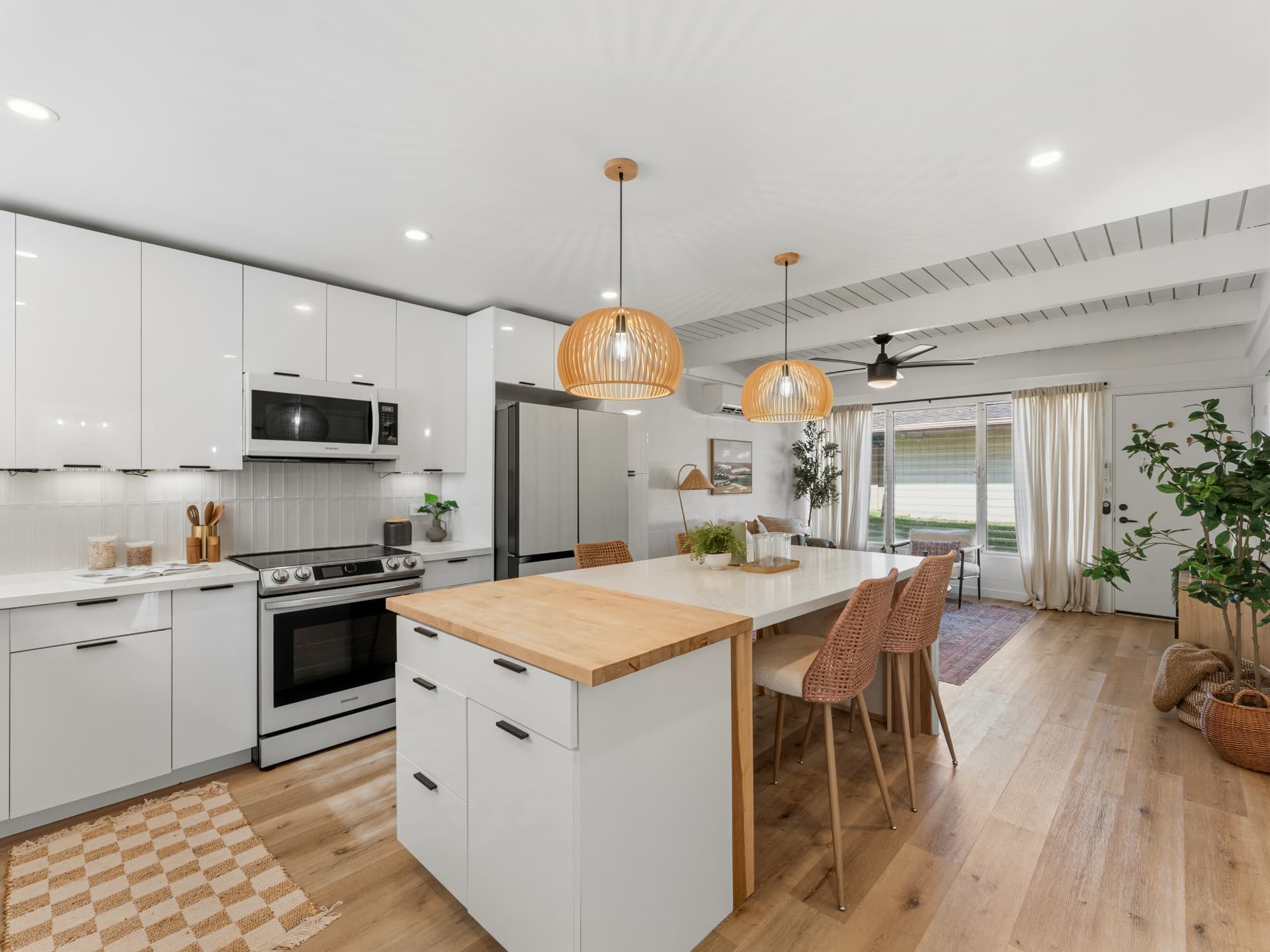 Open-concept kitchen with white cabinets and modern pendant lighting